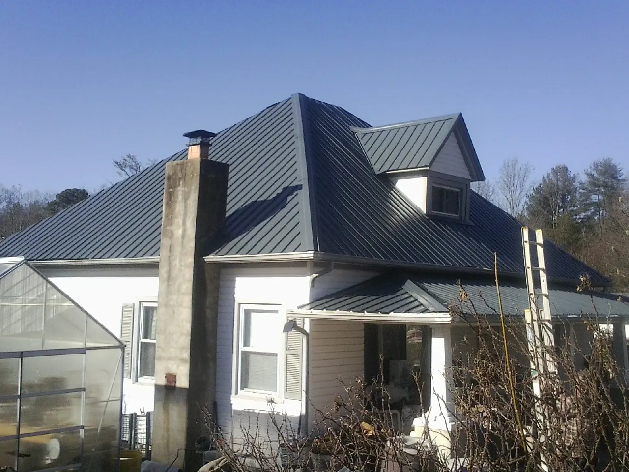 Dark blue standing seam metal roof on a white farmhouse with dormer — Slate & Tile Roof Repair by Roofing Brothers in Succasunna