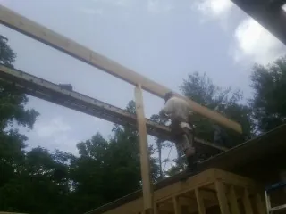 Carpenter setting a ridge beam over a new addition frame — Ice Dam Removal by Roofing Brothers in Succasunna