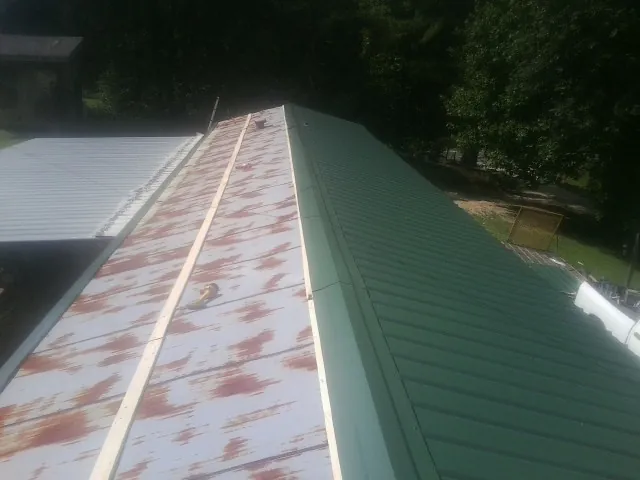 Old rusted panels beside newly installed green metal roofing — Wind Damage Roof Repair by Roofing Brothers in Succasunna