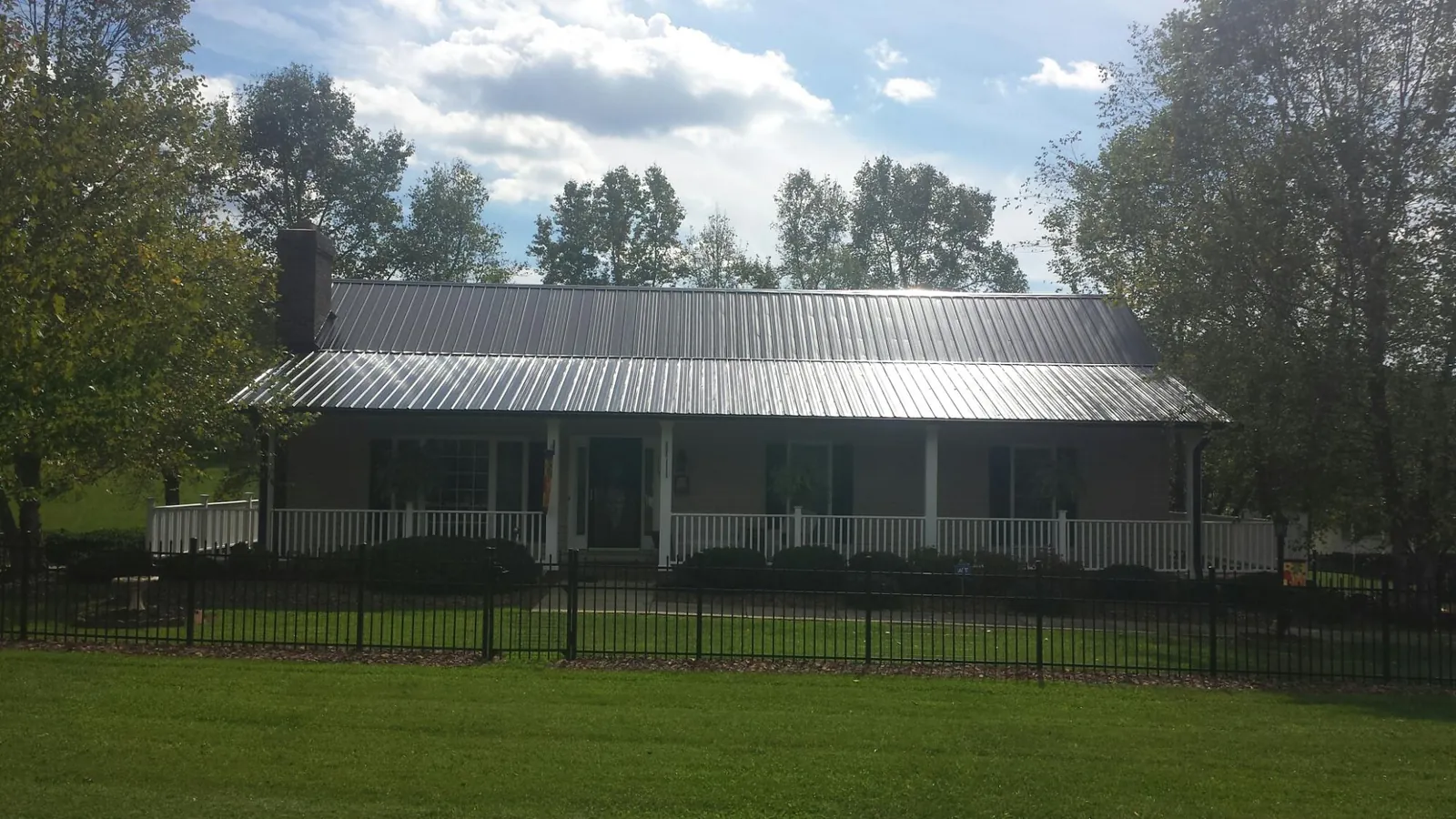 Gray metal roof on a brick ranch with a full width front porch — Gutter Guard Installation work by our crew in Succasunna